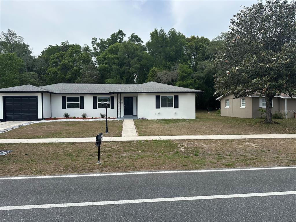 A single-story house with a white exterior, black shutters, and an attached garage — 9330 N CITRUS SPRINGS BOULEVARD, CITRUS SPRINGS, FL
