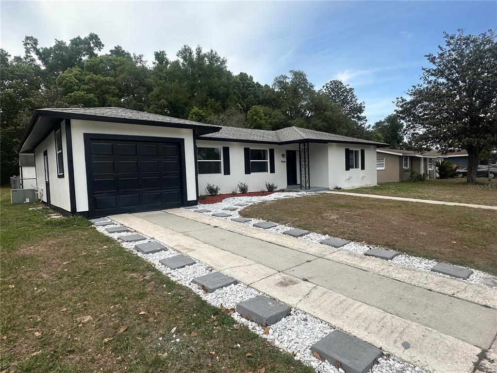 A single-story house with a white exterior, black trim, a garage, and a paved driveway — 9330 N CITRUS SPRINGS BOULEVARD, CITRUS SPRINGS, FL