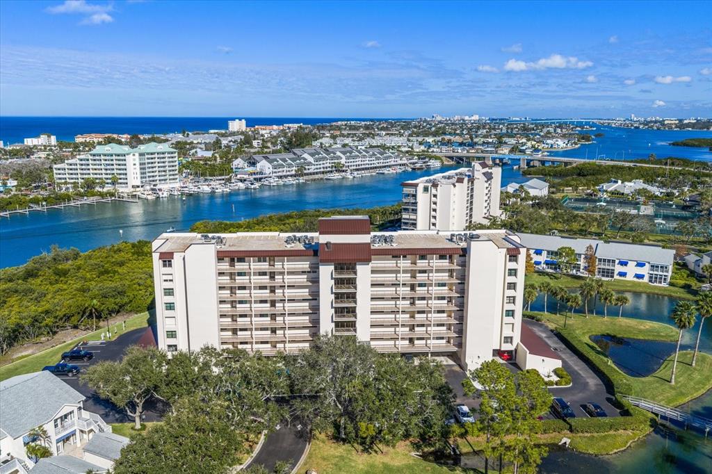 An aerial view of a multi-story apartment building situated near a waterway and bridge — 11590 SHIPWATCH DRIVE UNIT 447, LARGO, FL