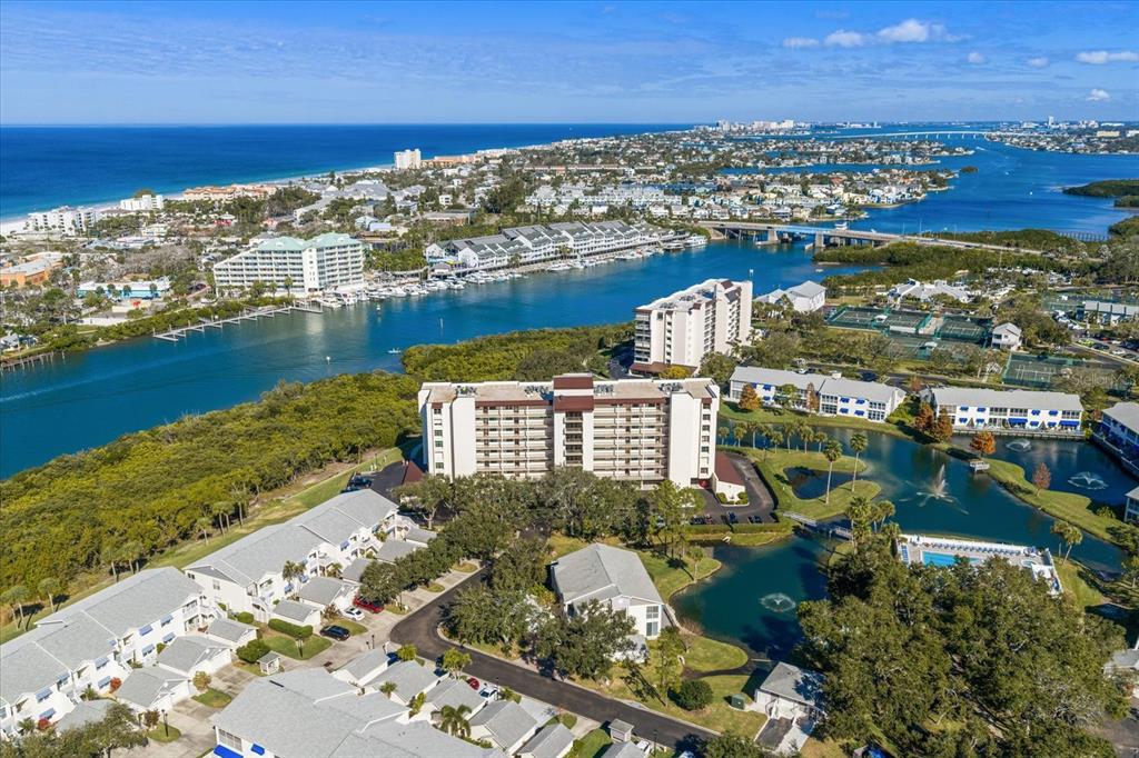 An aerial view shows a multi-story residential building surrounded by ponds, trees, and coastal waterways — 11590 SHIPWATCH DRIVE UNIT 447, LARGO, FL