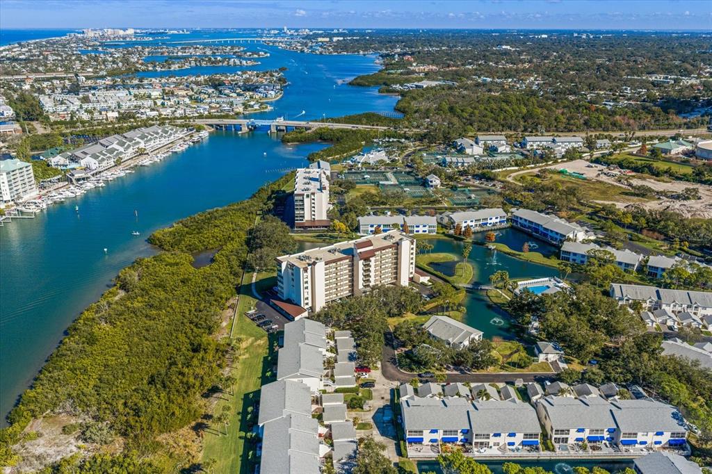 An aerial view shows a waterfront condominium complex with a pool and tennis courts — 11590 SHIPWATCH DRIVE UNIT 447, LARGO, FL