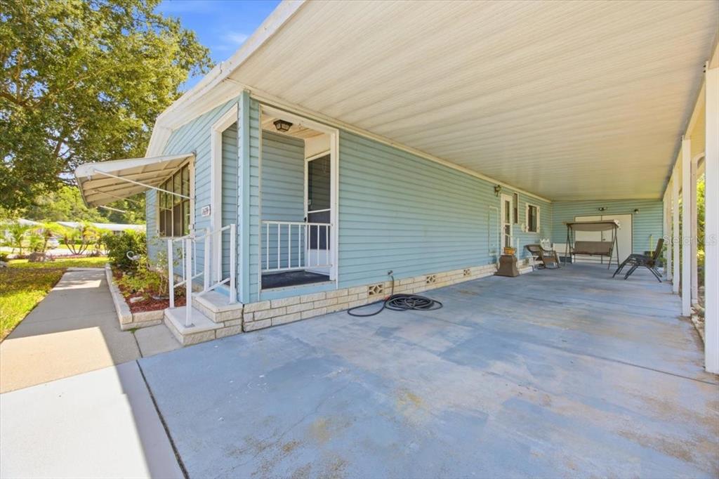 A light blue mobile home features a large concrete carport and a small front porch — 2679 LAKE GRASSMERE CIRCLE UNIT 903, ZELLWOOD, FL