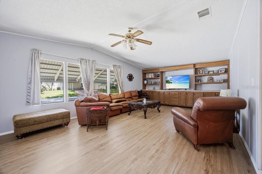 A living room features wood-look flooring, a leather sectional, a matching armchair, and built-in shelving — 2679 LAKE GRASSMERE CIRCLE UNIT 903, ZELLWOOD, FL