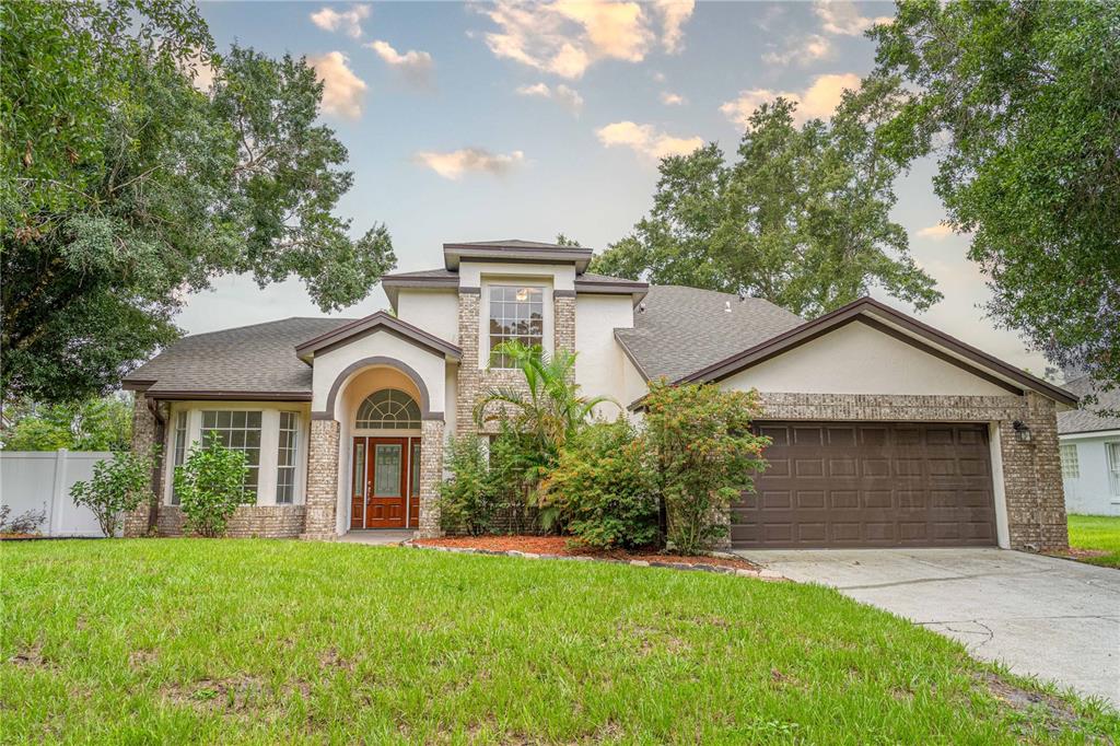 A two-story suburban house with a brick and stucco facade, arched entryway, and attached garage — 515 BENTLEY STREET, OVIEDO, FL