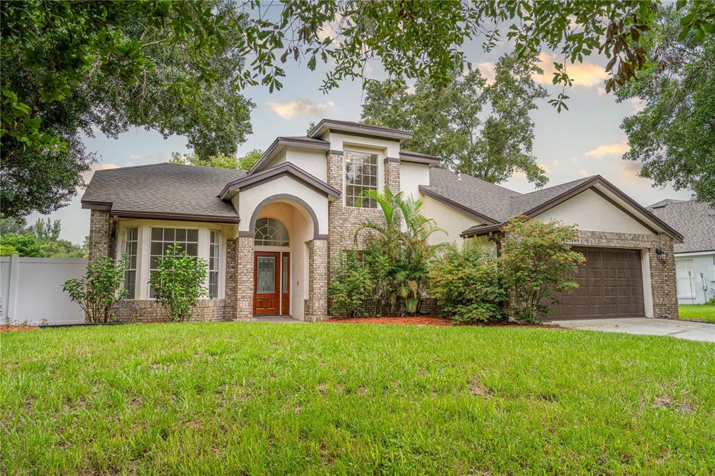 A single-story house with a brick and stucco exterior, arched entryway, and attached two-car garage — 515 BENTLEY STREET, OVIEDO, FL