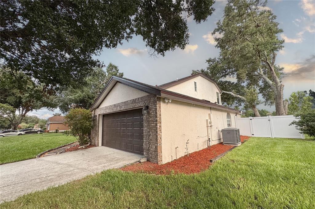 A side view of a house exterior featuring a garage, stucco walls, and a lawn — 515 BENTLEY STREET, OVIEDO, FL