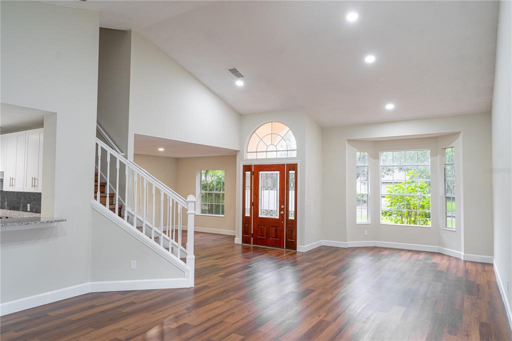 An open living area features wood flooring, a staircase, and a front door with windows — 515 BENTLEY STREET, OVIEDO, FL