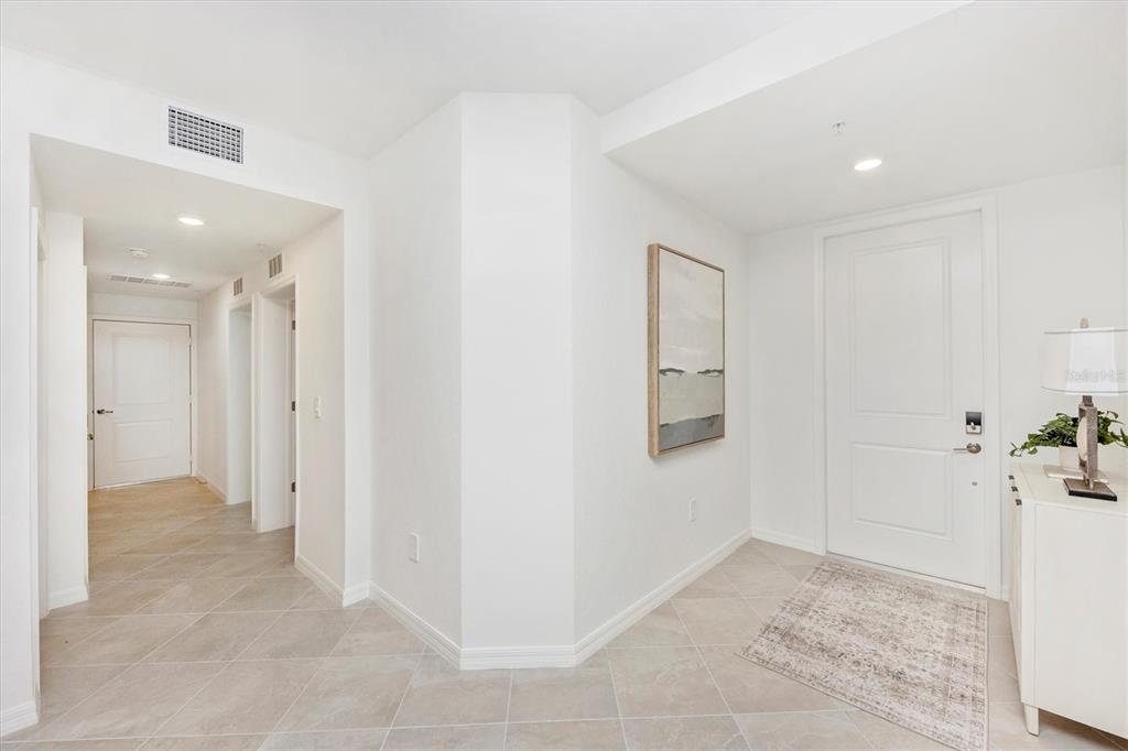 A bright entryway features white walls, tile flooring, a white door, and a framed painting — 12620 RADIANCE COURT UNIT 101, VENICE, FL