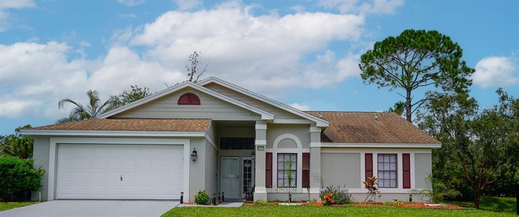 A single-story house with a two-car garage, beige siding, and a brown shingled roof — 8141 GOLF CLUB COURT, HUDSON, FL