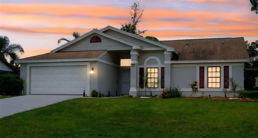 A single-story house with a two-car garage, light-colored stucco exterior, and dark red shutters — 8141 GOLF CLUB COURT, HUDSON, FL