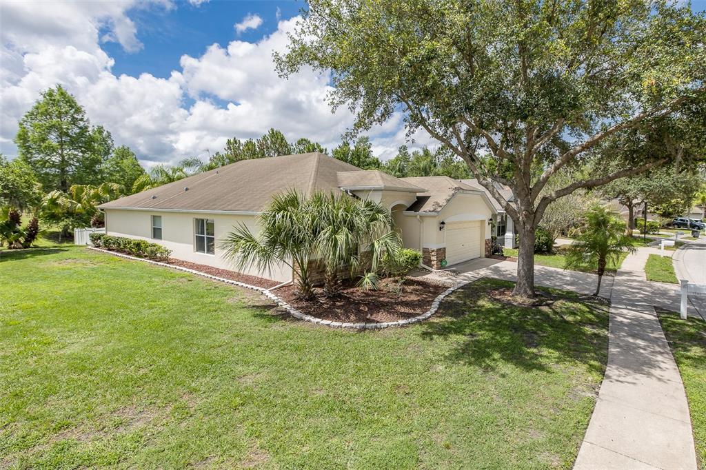 A single-story house with a tan exterior, a two-car garage, and a large front yard — 13312 OLD FLORIDA CIRCLE, HUDSON, FL