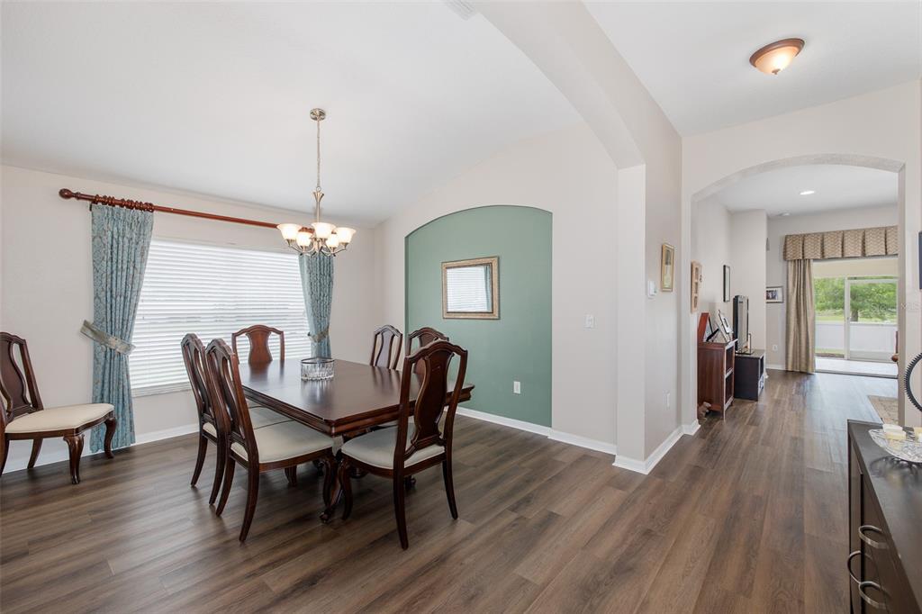 A dining room features a dark wood table, chairs, and an arched green accent wall — 13312 OLD FLORIDA CIRCLE, HUDSON, FL