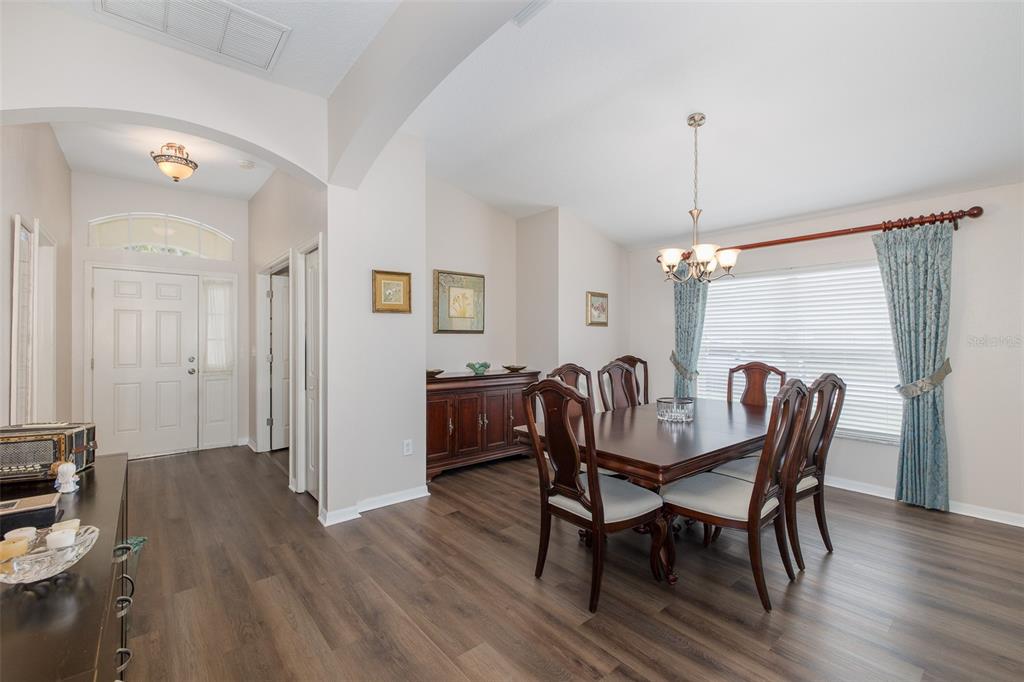 A dining room with a wooden table, chairs, and a sideboard on wood-look flooring — 13312 OLD FLORIDA CIRCLE, HUDSON, FL