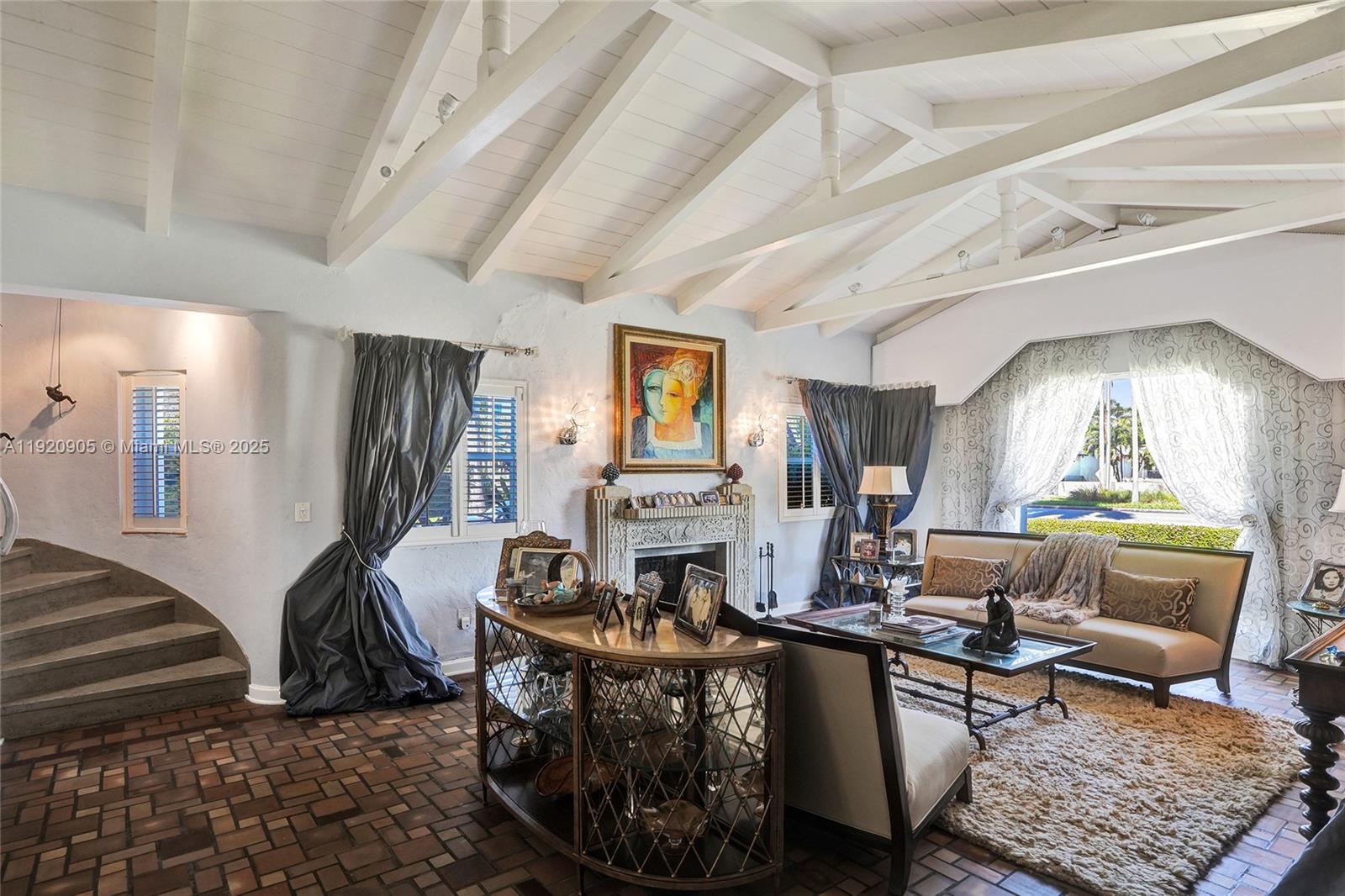 A living room features a vaulted ceiling, brick flooring, a fireplace, and a curved staircase — 940 Hollywood Blvd, Hollywood FL 33019, HOLLYWOOD, FL