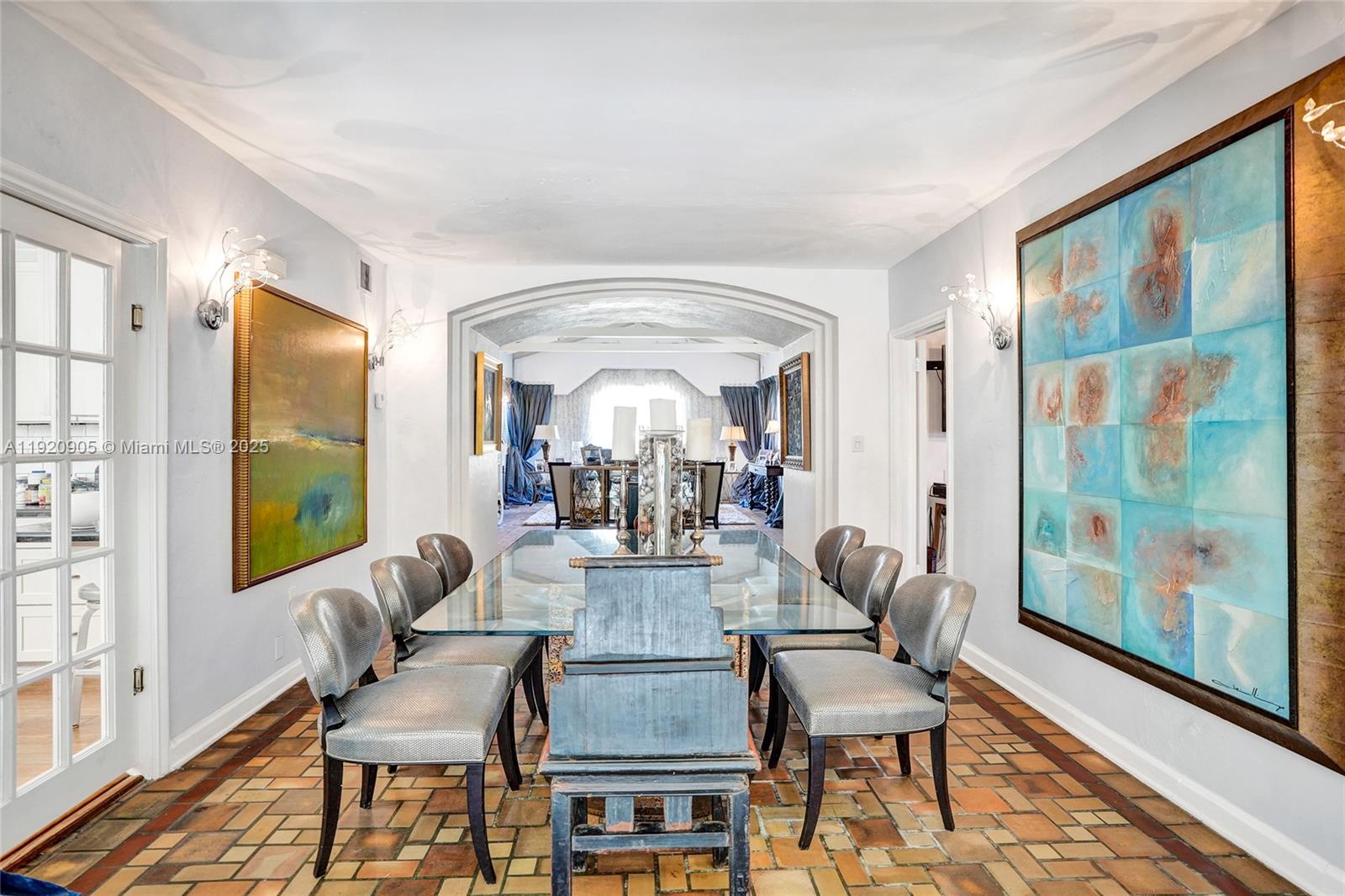 A dining room features a glass table, gray chairs, and tile flooring under an archway — 940 Hollywood Blvd, Hollywood FL 33019, HOLLYWOOD, FL