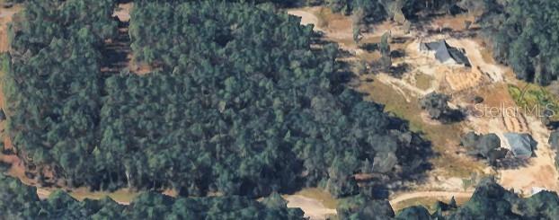 An aerial view shows a wooded lot adjacent to a cleared area with two houses — TBD, MELROSE, FL