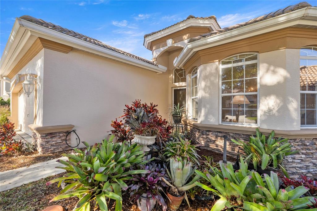 The exterior of a house features a stone-accented facade, a tiled roof, and landscaped garden beds — 389 W DOERR PATH, HERNANDO, FL