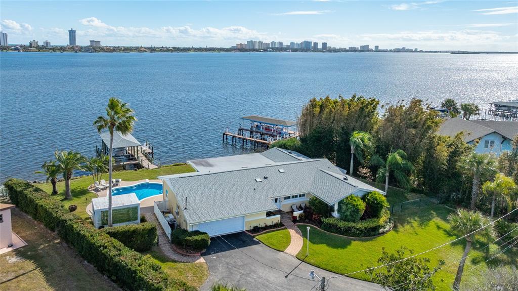 An aerial view of a waterfront house with a pool, boat dock, and paved driveway — 130 REEF ROAD, SOUTH DAYTONA, FL