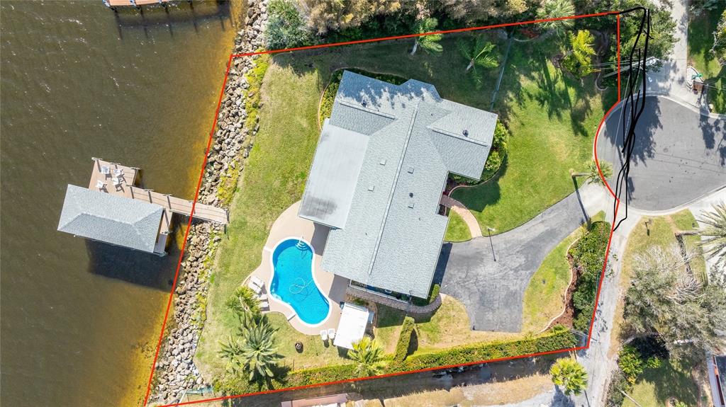 An aerial view shows a waterfront house with a pool, dock, and paved driveway — 130 REEF ROAD, SOUTH DAYTONA, FL
