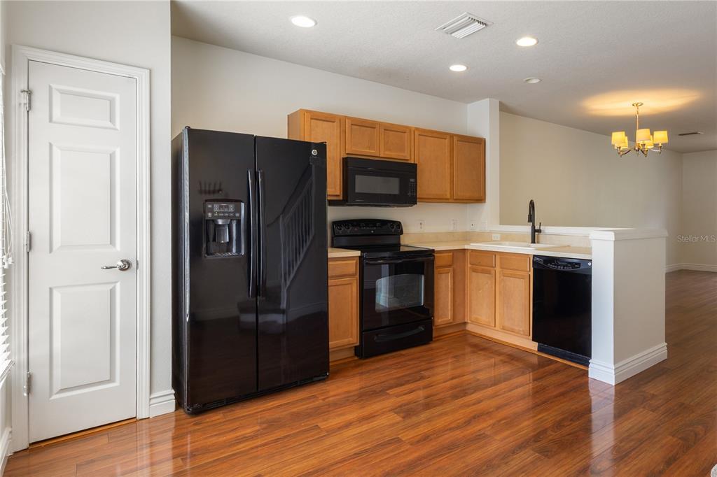 A kitchen with wood cabinets, black appliances, and hardwood flooring — 10445 WESTPARK PRESERVE BOULEVARD, TAMPA, FL