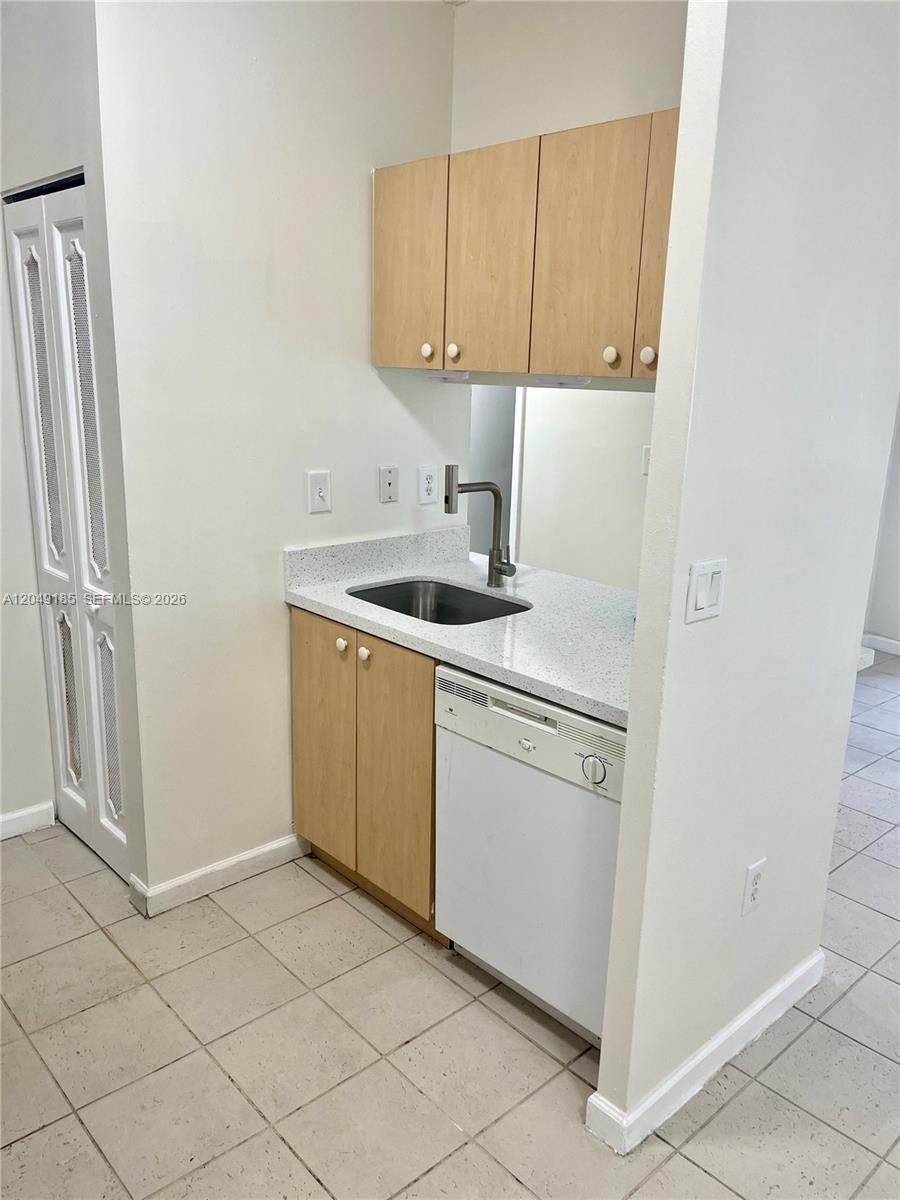 A small kitchen area features light wood cabinets, a white dishwasher, and a stone countertop — 15699 SW 73rd Cir Ter # 11, Miami FL 33193, MIAMI, FL