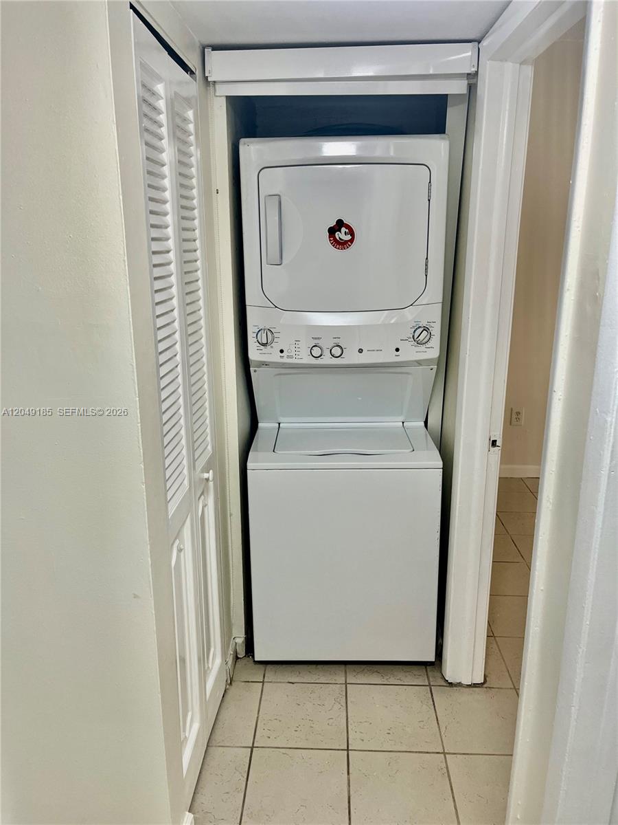 A stacked washer and dryer unit is located in a small tiled laundry closet — 15699 SW 73rd Cir Ter # 11, Miami FL 33193, MIAMI, FL