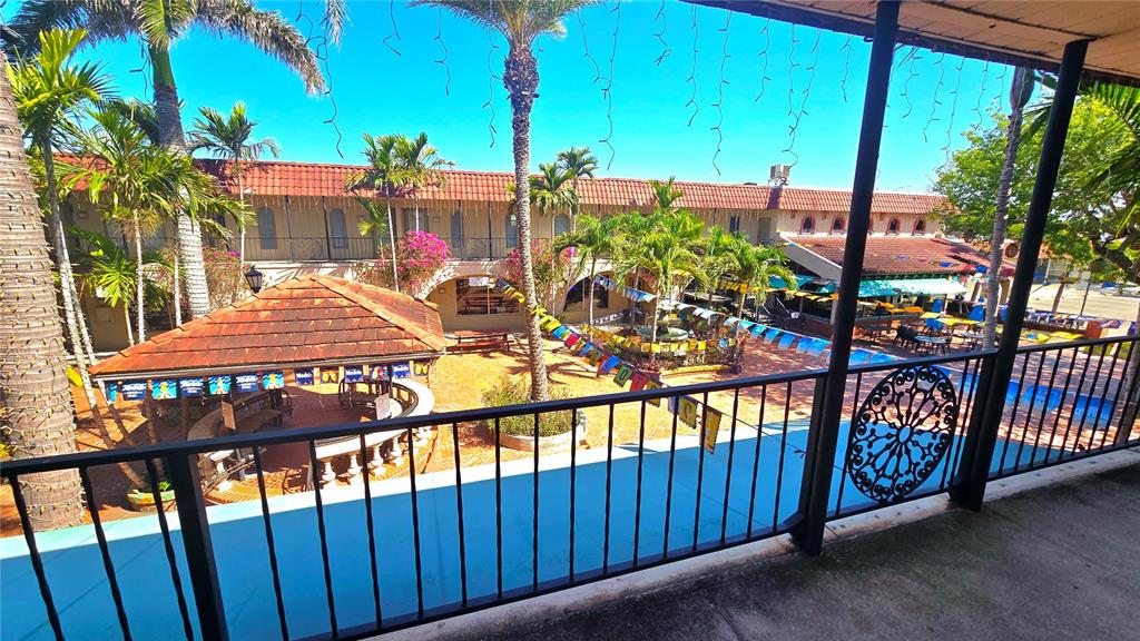 An elevated view of a courtyard with a tiki bar, palm trees, and pool area — 530 US-41-BYP UNIT 20-21B, VENICE, FL