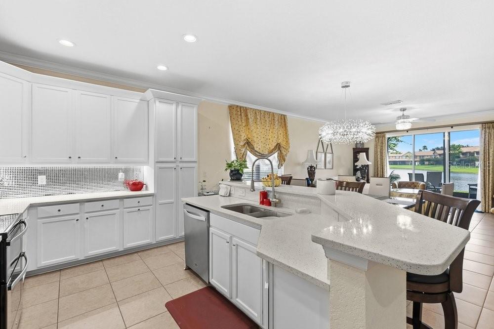 A kitchen with white cabinets, a quartz island, and tile flooring overlooking a backyard lake — 10722 BELFRY CIRCLE, ORLANDO, FL