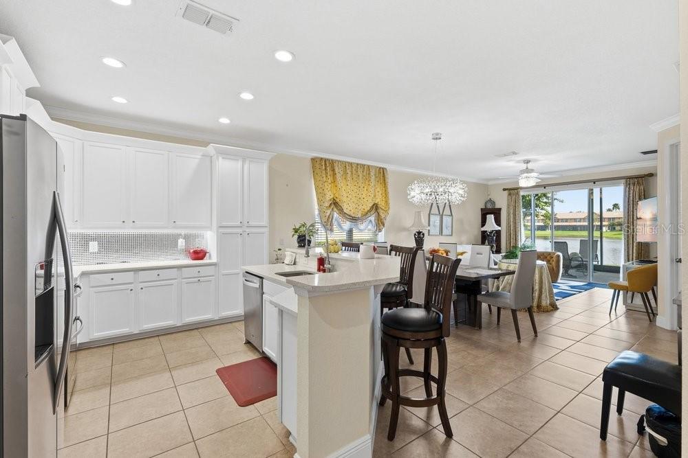 A kitchen with white cabinets and a breakfast bar opens to a dining area with views — 10722 BELFRY CIRCLE, ORLANDO, FL