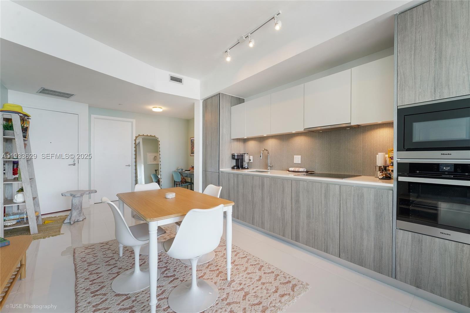 A modern kitchen features wood-grain lower cabinets, white upper cabinets, and a dining area — 2900 NE 7th Ave # 3108, Miami FL 33137, MIAMI, FL