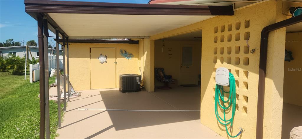 A covered patio area features a concrete floor, a yellow exterior wall, and a hose reel — 1700 MORNING DOVE LANE, ENGLEWOOD, FL
