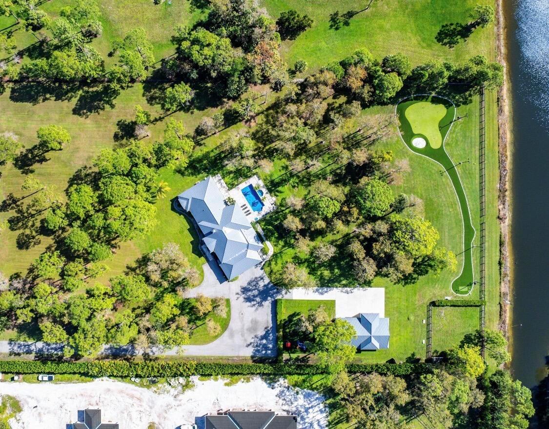 Aerial view of a house with a pool and a private putting green near water — 11230 Alligator Trail, Lake Worth FL 33449, LAKE WORTH, FL