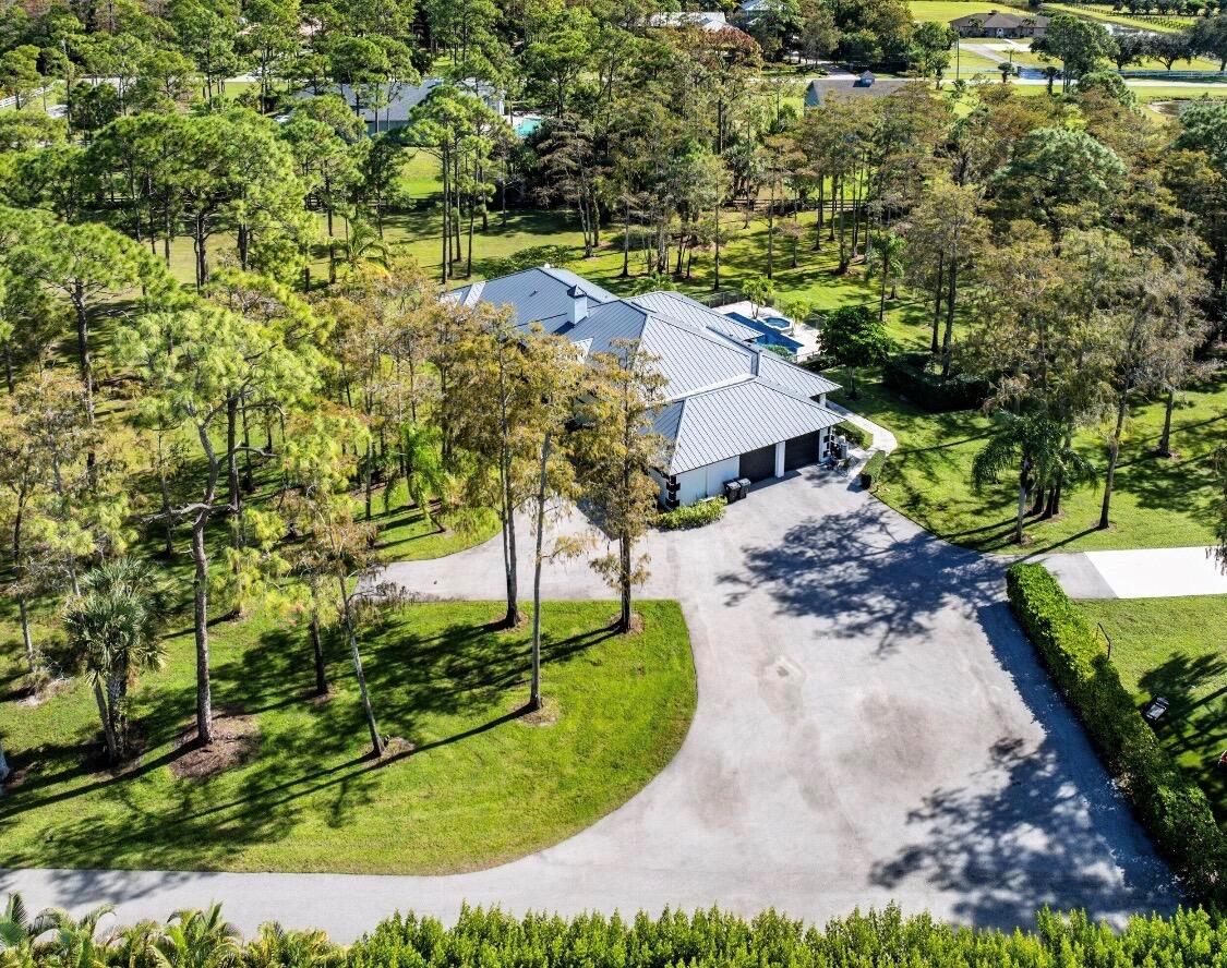 An aerial view of a house with a metal roof, driveway, and surrounding wooded yard — 11230 Alligator Trail, Lake Worth FL 33449, LAKE WORTH, FL