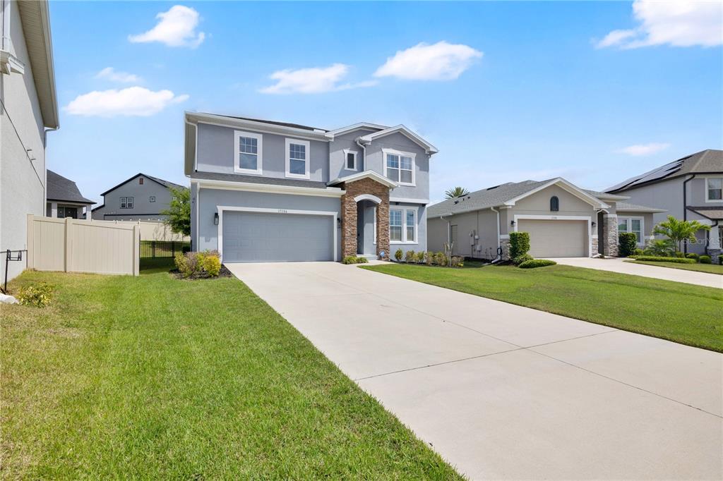 A two-story gray house with a stone entryway and a two-car garage — 17186 HICKORY WIND DRIVE, CLERMONT, FL