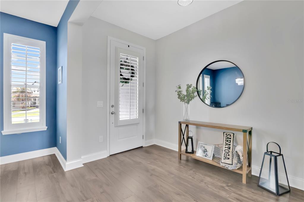 An entryway features light wood flooring, a blue accent wall, and a wooden console table — 17186 HICKORY WIND DRIVE, CLERMONT, FL