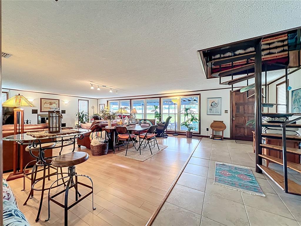 A spacious living and dining area features a spiral staircase, tile flooring, and large windows — 7001 JONES AVENUE, MOUNT DORA, FL