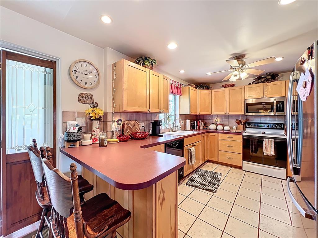 A kitchen features light wood cabinets, a red countertop, and tile flooring — 7001 JONES AVENUE, MOUNT DORA, FL