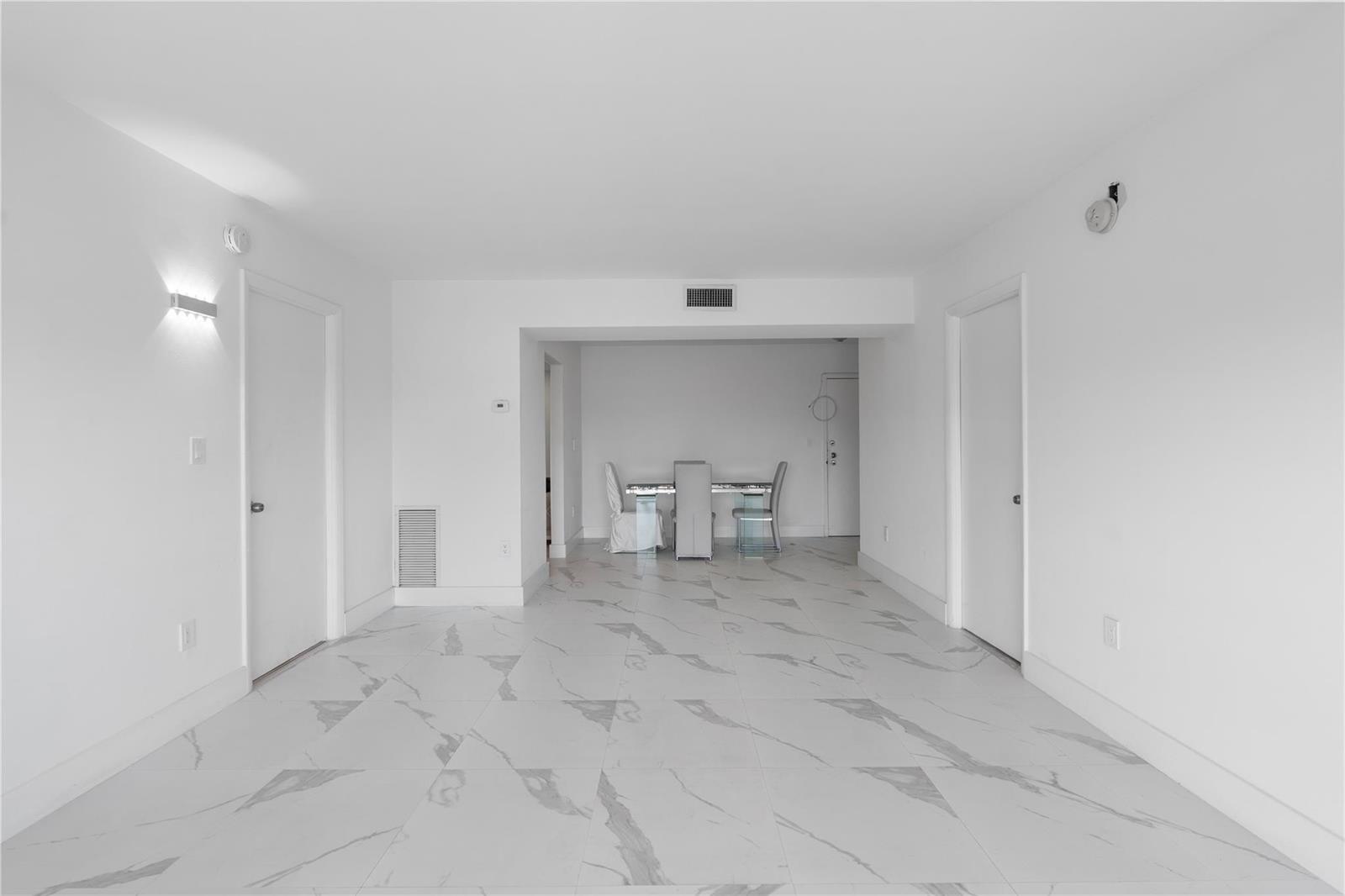 An empty room with white walls, white marble-patterned tile floors, and a dining set — 4164 Inverrary Drive # 412, Lauderhill FL 33319, LAUDERHILL, FL