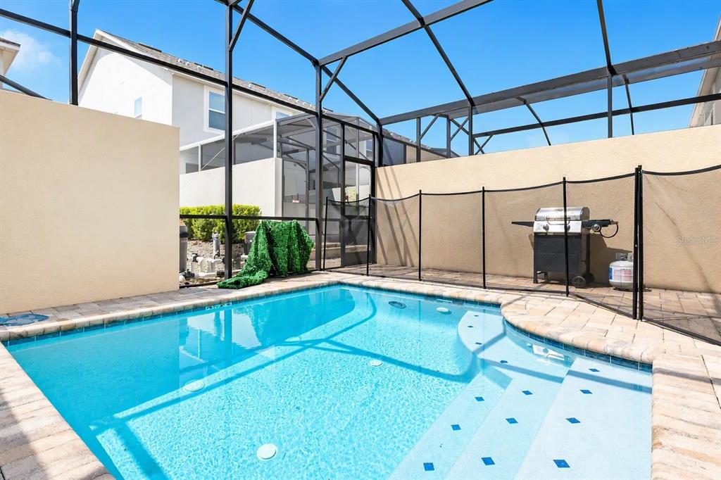 A swimming pool with a screen enclosure and a grill on a paved patio — 1562 CAREY PALM CIRCLE, KISSIMMEE, FL
