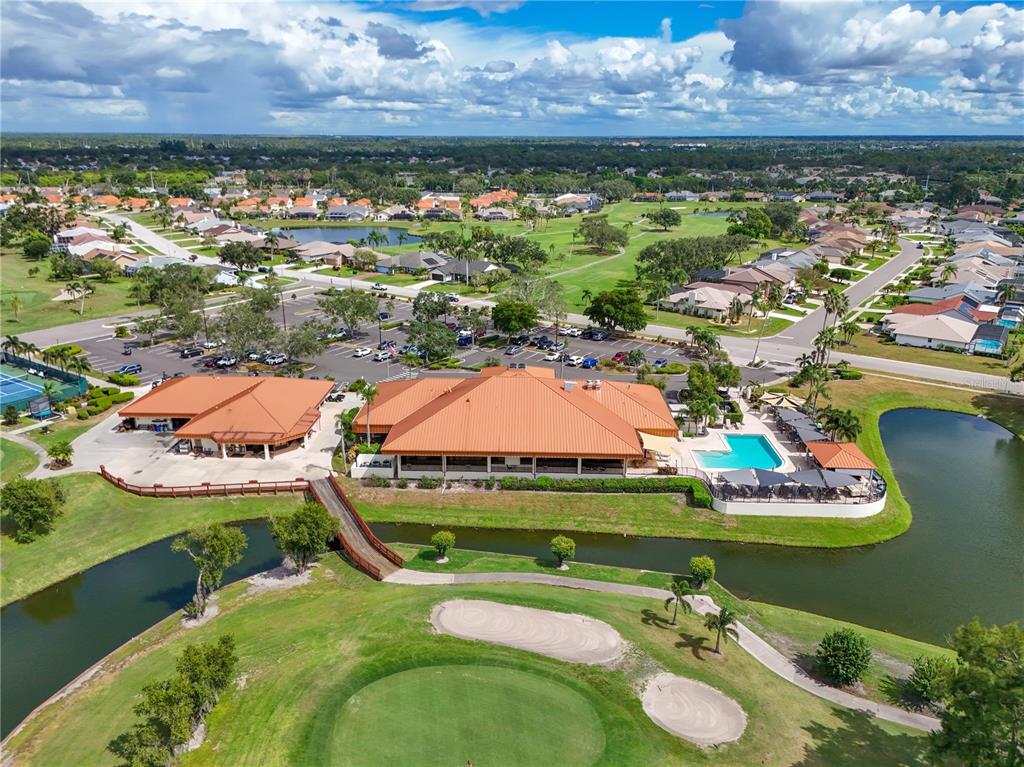 An aerial view shows a clubhouse with a red roof, pool, and surrounding golf course — 4705 SAND TRAP STREET CIRCLE E UNIT 105, BRADENTON, FL
