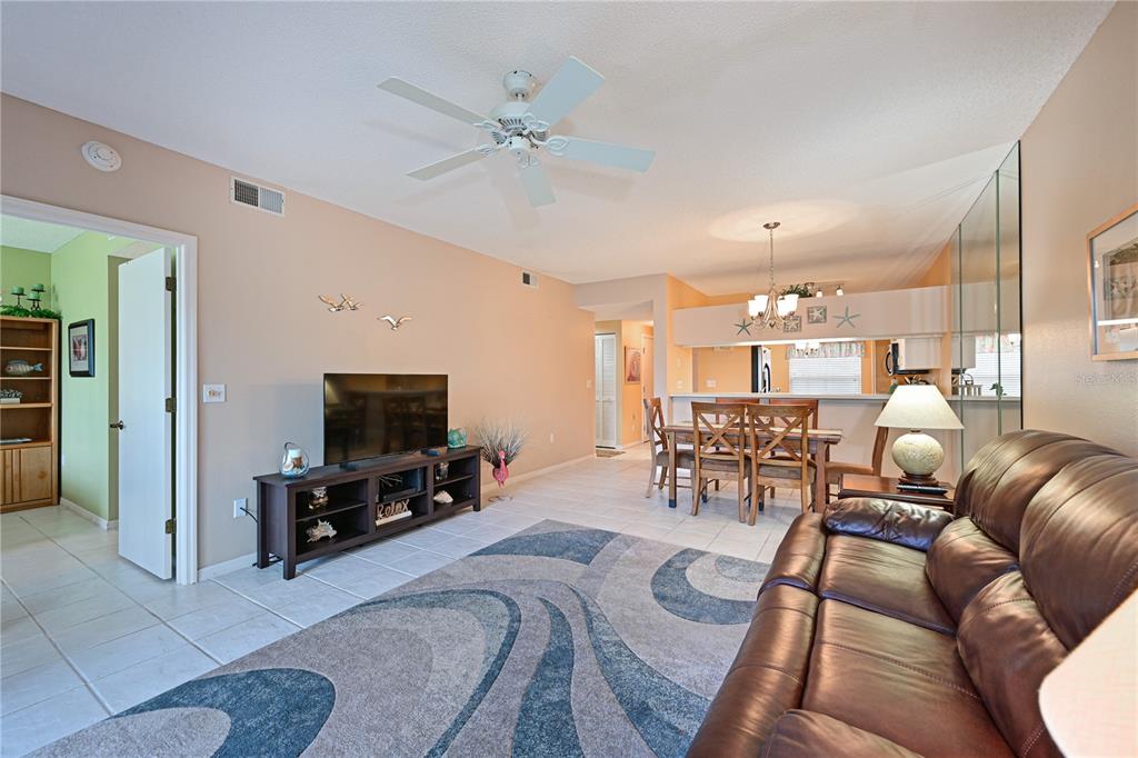 A living room with tile floors, a brown leather sofa, and a dining area — 4705 SAND TRAP STREET CIRCLE E UNIT 105, BRADENTON, FL