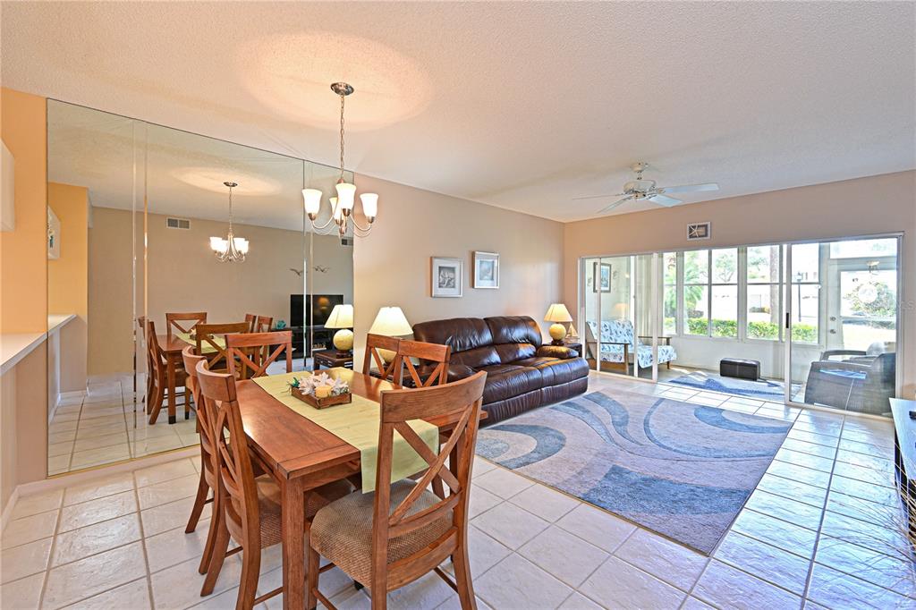 A dining area and living room with tiled floors, a mirrored wall, and sliding glass doors — 4705 SAND TRAP STREET CIRCLE E UNIT 105, BRADENTON, FL