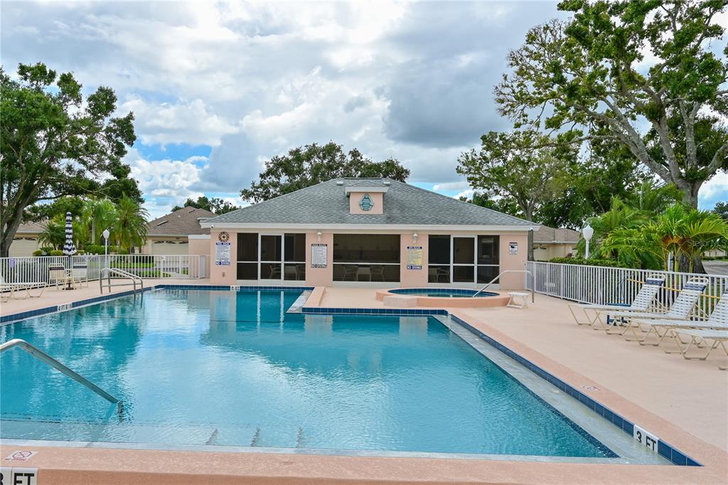 A community swimming pool and hot tub sit in front of a clubhouse building — 4705 SAND TRAP STREET CIRCLE E UNIT 105, BRADENTON, FL