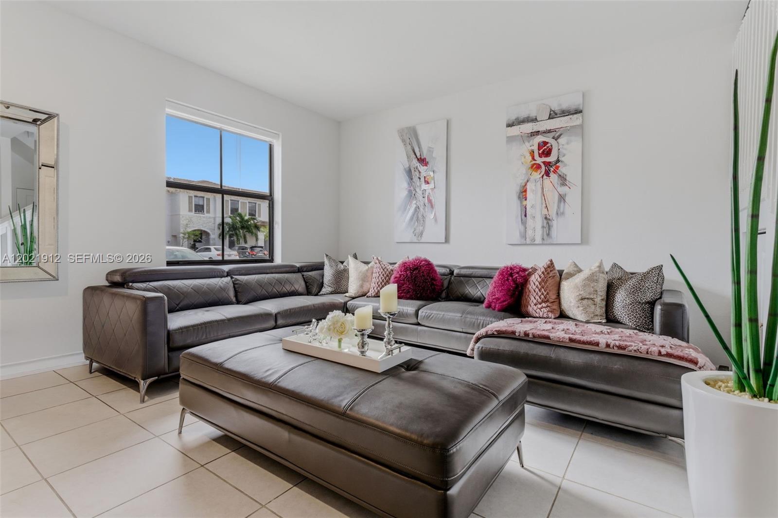 A living room features a large gray sectional sofa, a matching ottoman, and abstract wall art — 10009 SW 228th Ter, Miami FL 33190, MIAMI, FL