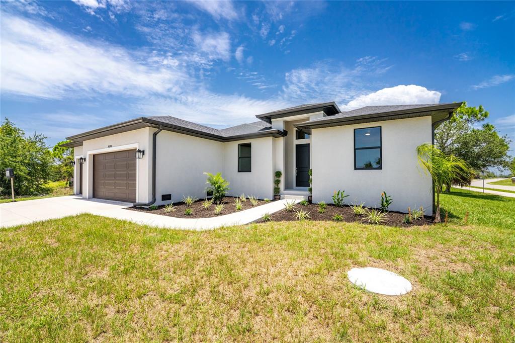 A single-story house with a white stucco exterior, a brown garage door, and a walkway — 9590 HONEYMOON DRIVE, PORT CHARLOTTE, FL