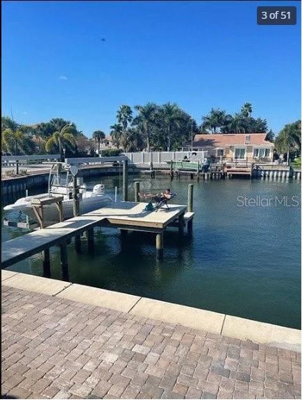 A boat is docked at a wooden pier in a canal behind a residential house — 2001 HAWAII AVENUE NE, ST PETERSBURG, FL