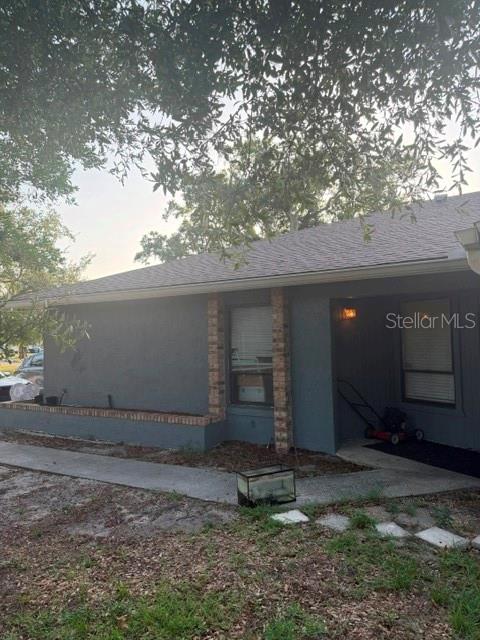 The exterior of a gray house features a brick-accented window and a covered entryway — 4604 FERN PINE DRIVE, ORLANDO, FL