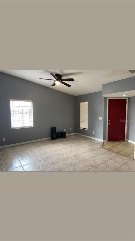 An empty living room with light gray walls, tile flooring, and a red front door — 4604 FERN PINE DRIVE, ORLANDO, FL