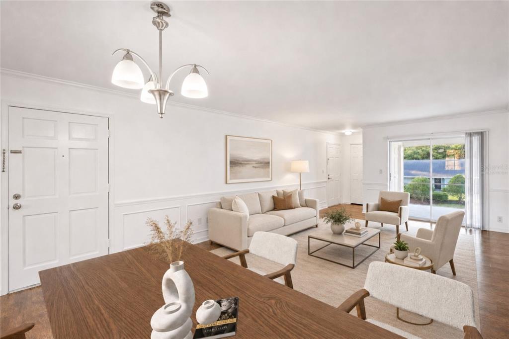 A bright living and dining area features white walls, wainscoting, a chandelier, and sliding doors — 3402 LATANIA DRIVE UNIT 321, TAMPA, FL