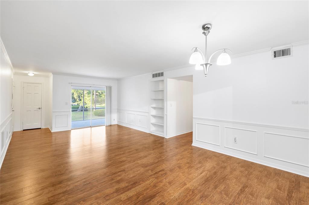 A bright dining room with white wainscoting, wood flooring, a chandelier, and a sliding glass door — 3402 LATANIA DRIVE UNIT 321, TAMPA, FL